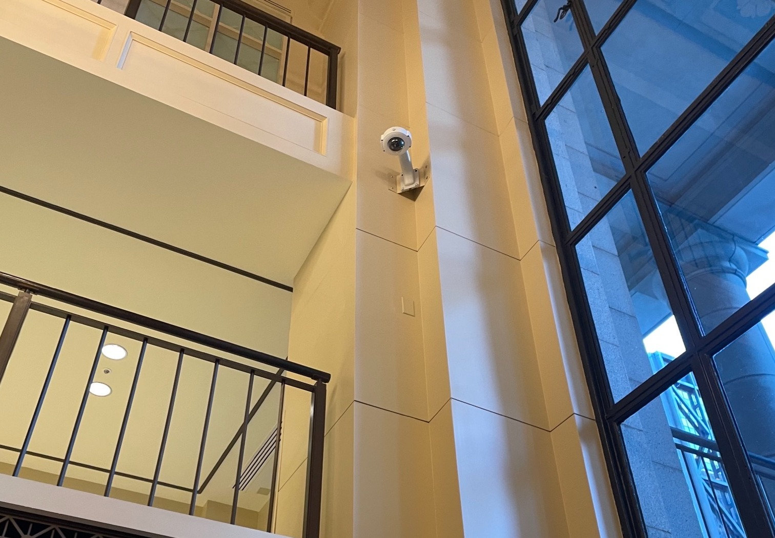 Photo of security camera in top corner of a a room near a window