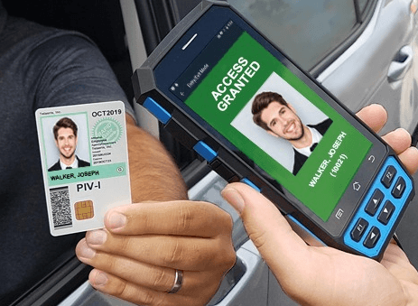 Close up photo of a person in car holding an ID badge. Another person scanning the badge with a handheld device to grant access.